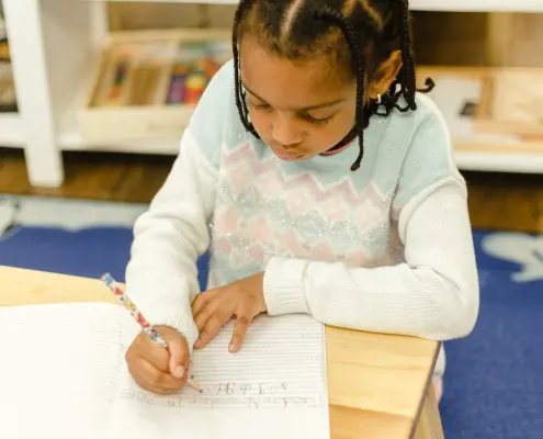 a student tracing sandpaper letters to learn the alphabet by touch