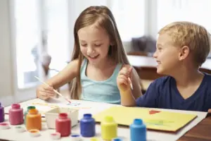 Two Children Painting Picture At Home students sharing Montessori materials, encouraging cooperative learning